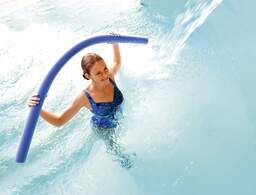 Eine junge Frau macht Wassergymnastik im Pool einer Therme von Bad Füssing.