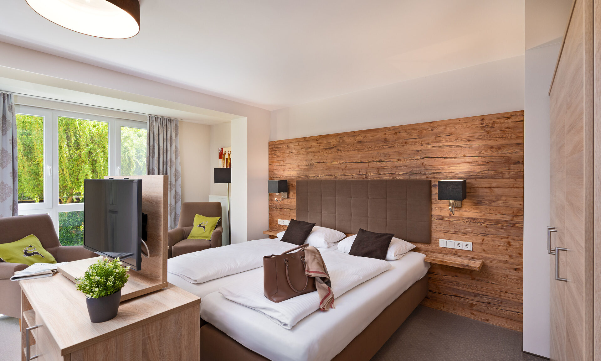 Ein helles Schlafzimmer mit einem Doppelbett und einem Fernseher im Richstein's Posthotel Bad Füssing.