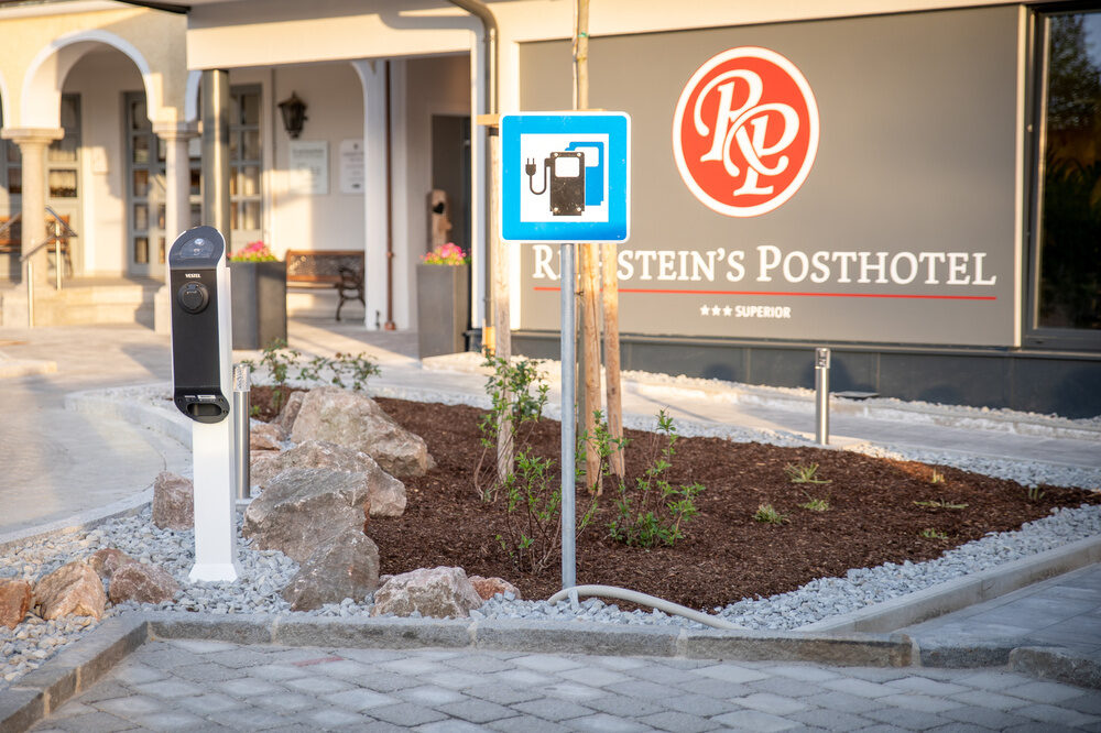 Ein Parkplatz mit Schild für die Aufladung von Elektroautos befindet sich vor dem Kurhotel Richstein's Posthotel Bad Füssing.
