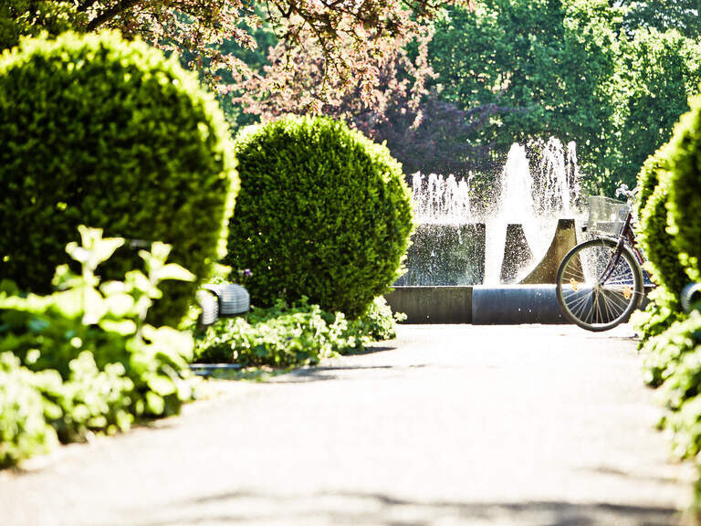 Ein Fahrrad steht inmitten des blühenden Gartens des Kurparks Bad Füssings