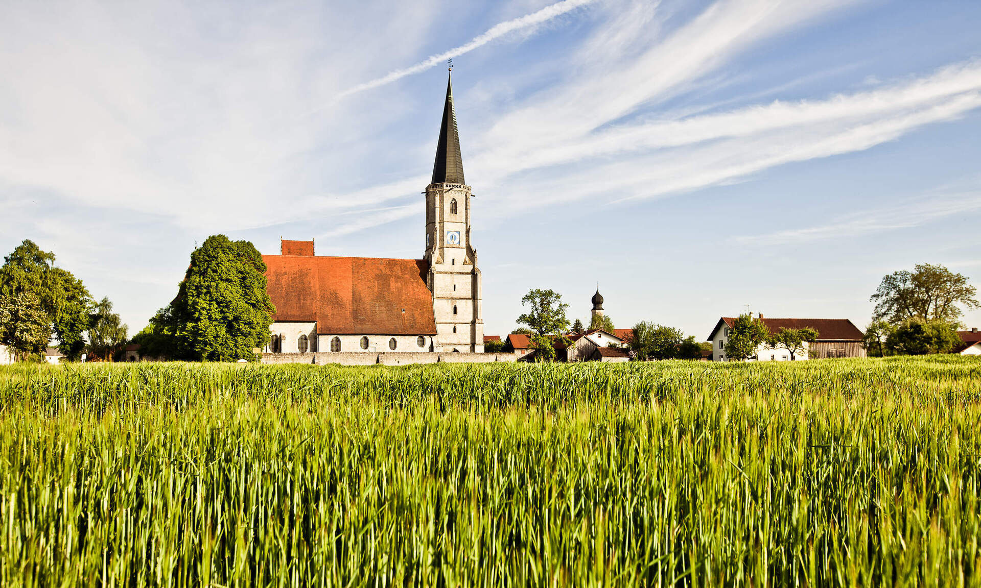 Eine Kirche ist umgeben von landwirtschaftlichen Feldern in der Region Bad Füssing.