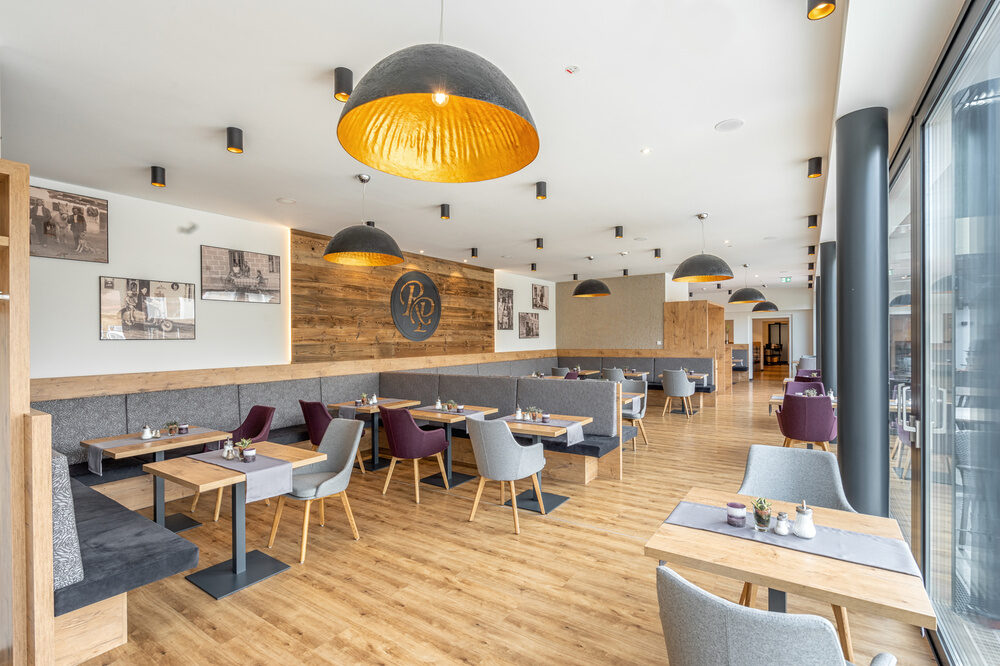 Elegante Tische und Stühle im Wintergarten des Richstein Posthotels schaffen ein einladendes Restaurantambiente.