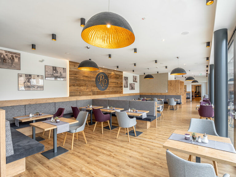 Elegante Tische und Stühle im Wintergarten des Richstein Posthotels schaffen ein einladendes Restaurantambiente.