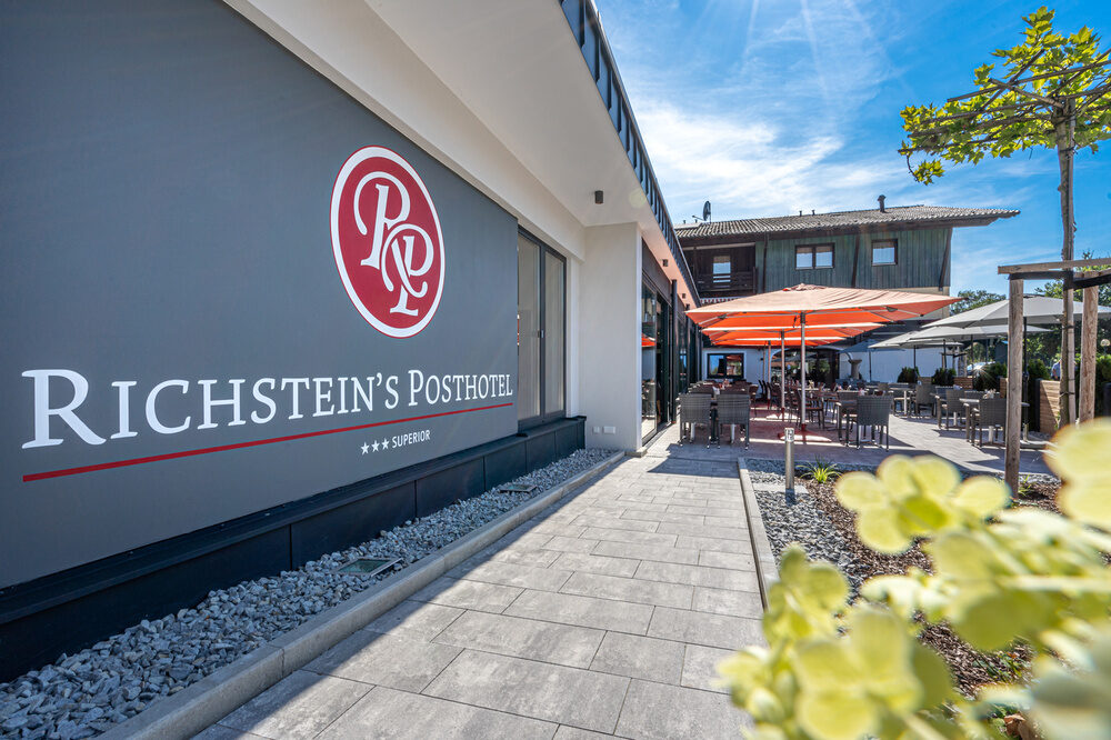Richsteinsposthotelgebäude mit Logo an der Fassade und Blick auf die Terrasse vom Hotel in Bad Füssing.
