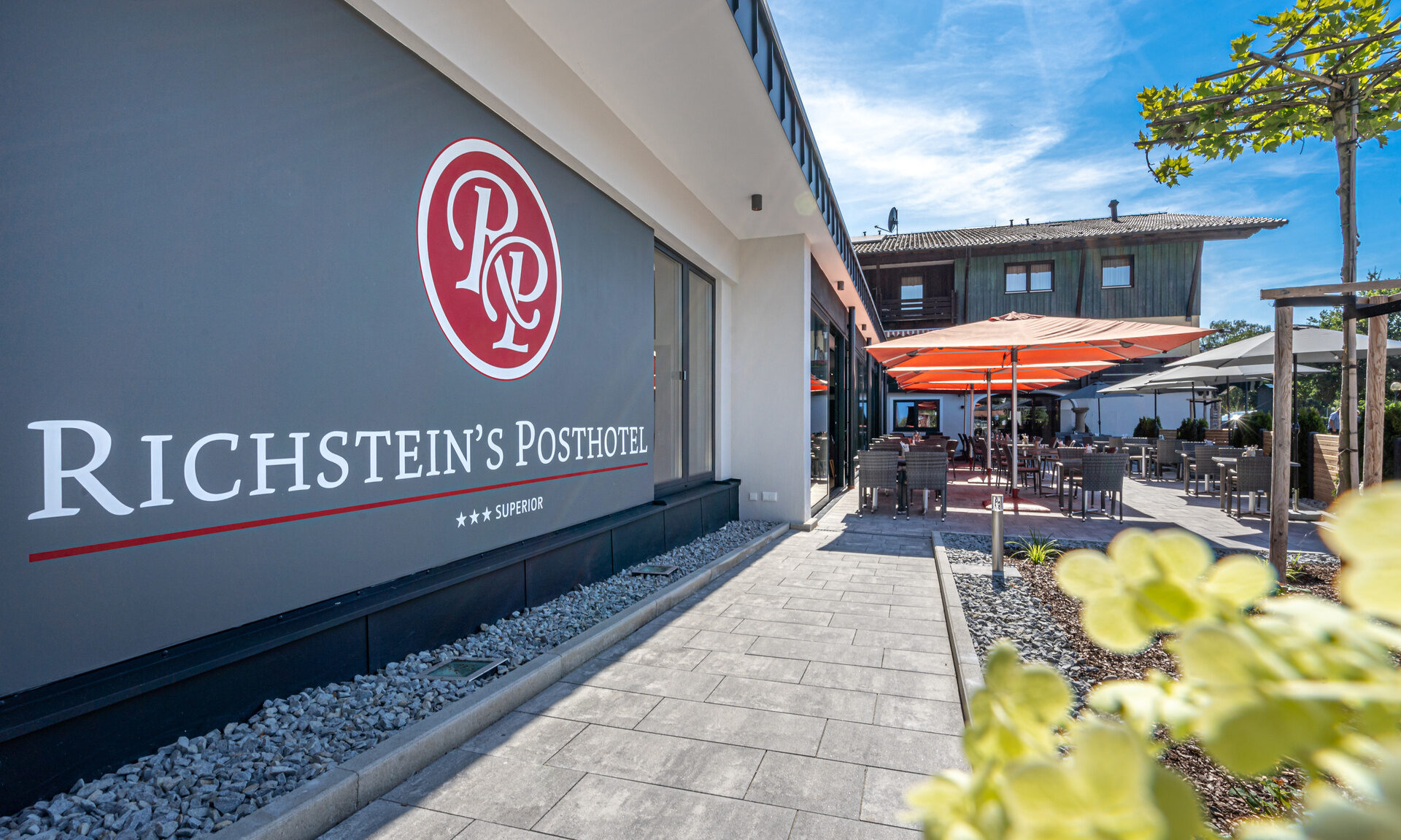 Richsteinsposthotelgebäude mit Logo an der Fassade und Blick auf die Terrasse vom Hotel in Bad Füssing.