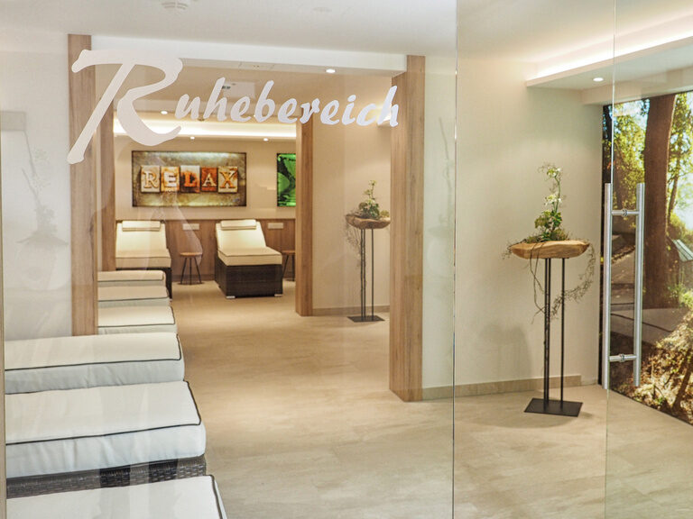 Der hell beleuchtete Zugang zum Ruhebereich mit vielen gemütlichen Liegen im Richstein's Wellneshotel Bad Füssing.