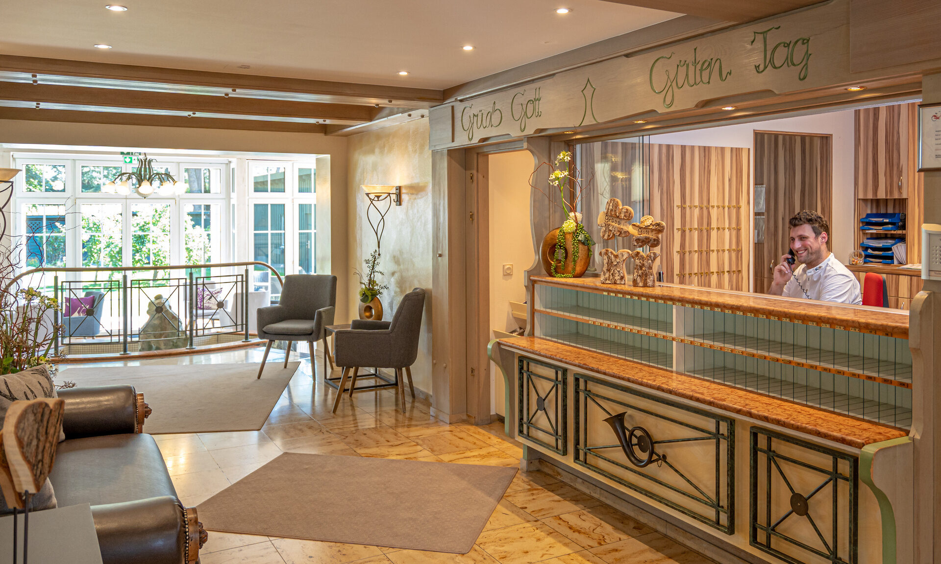 Die gemütliche Sitzgruppe mit Couches und Sesseln, umgeben von Pflanzen, lädt in der Rezeption zum Verweilen im Hotel ein.